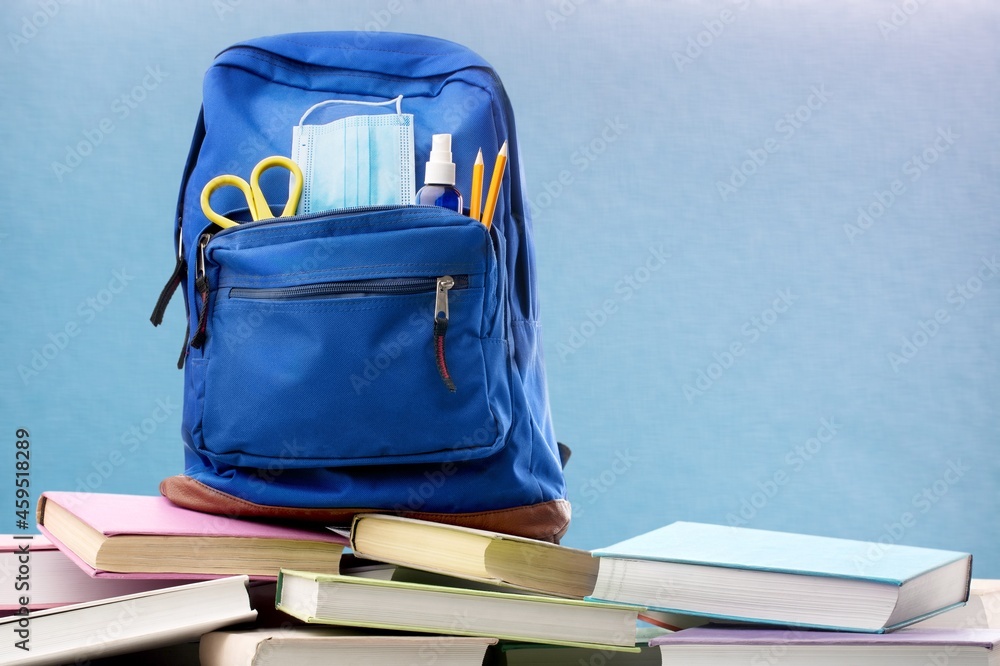 Classic school backpack with different school stationery on background