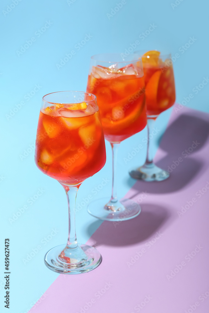 Glasses of Aperol spritz cocktail on color background