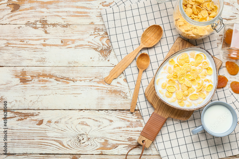 Composition with tasty cornflakes and milk on light wooden background