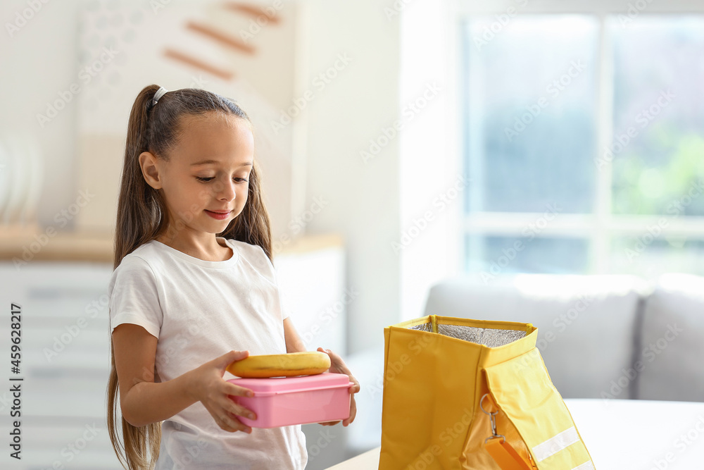 可爱的小女孩把她的午餐放在袋子里