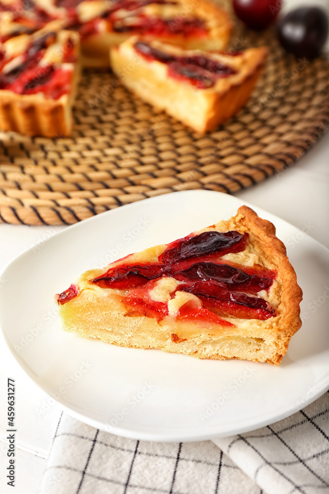 Plate with piece of tasty plum pie on light background, closeup