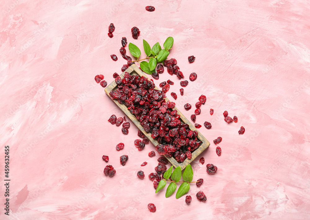 Board with tasty dried cranberries on color background