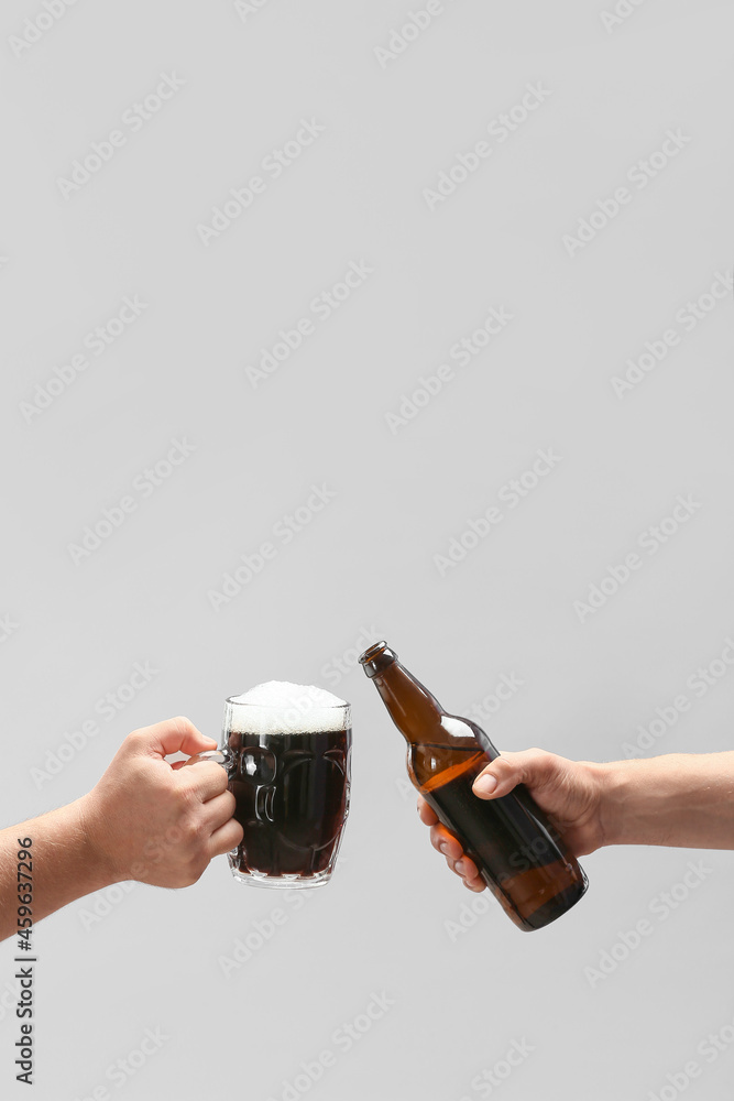 Hands with beer on grey background