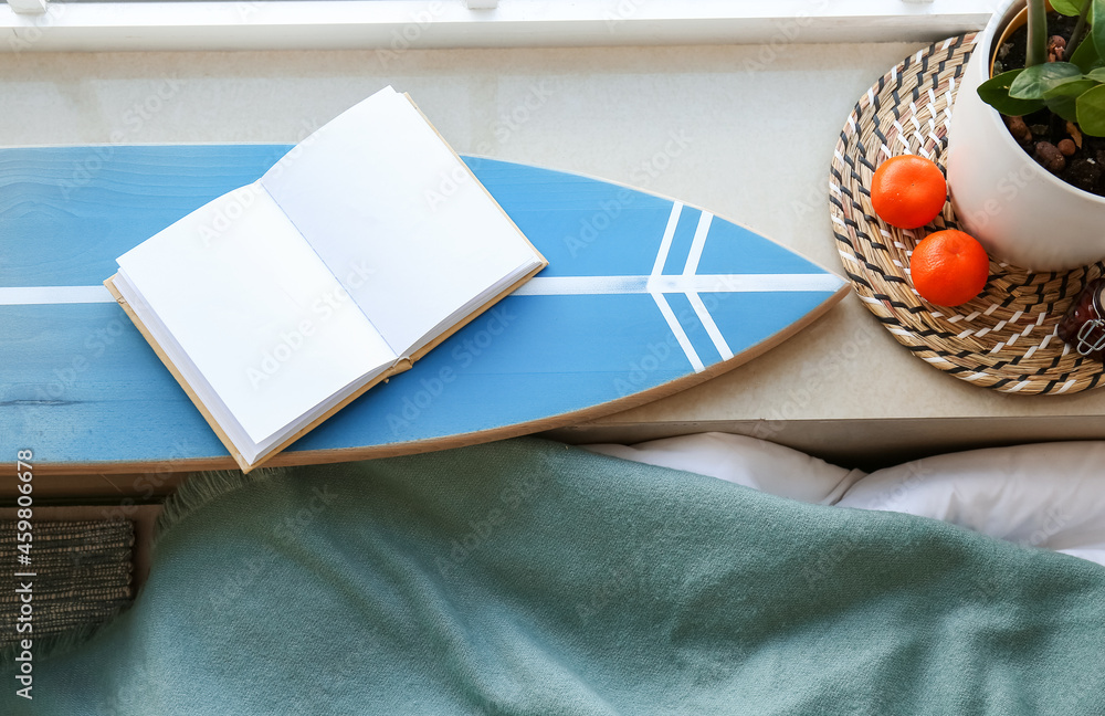 Surfboard with book on window sill in bedroom