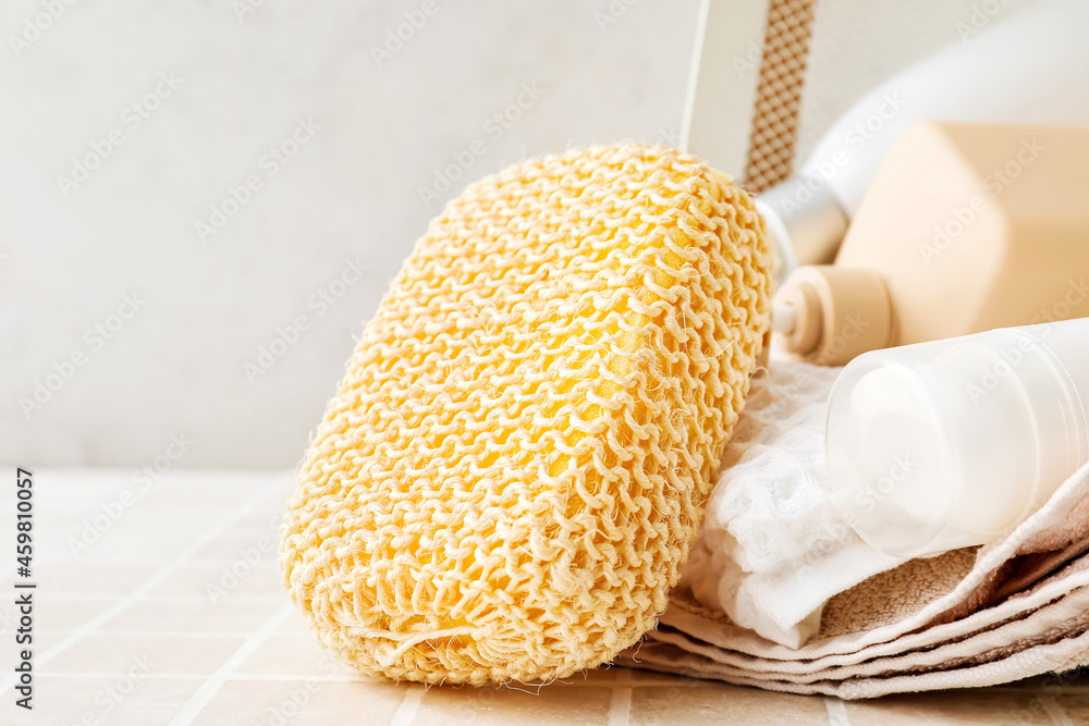 Loofah sponge with bath supplies and towels on table in bathroom