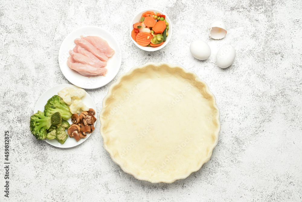 Raw dough and ingredients for preparing pot pie on light background