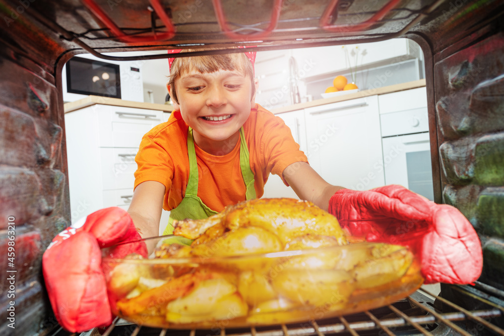 Happy smiling boy take fried chicken from oven