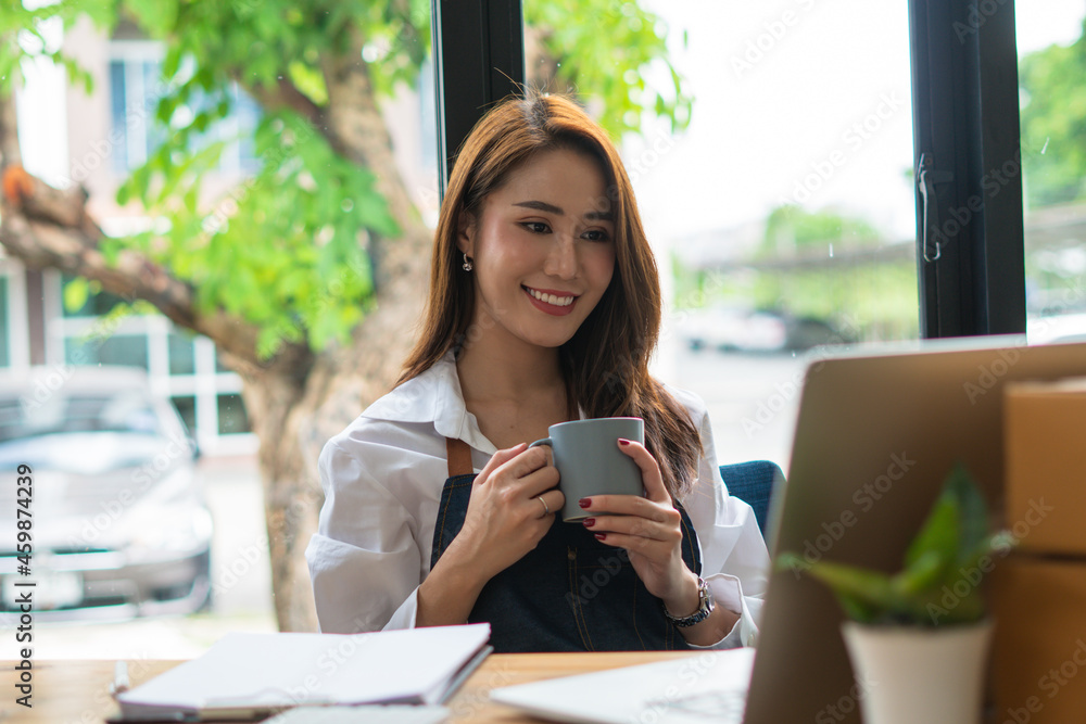 亚洲年轻女子在咖啡馆使用笔记本电脑的肖像，她在咖啡馆用笔记本电脑工作