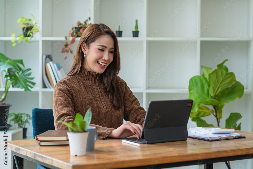 美丽微笑的亚洲女博主穿着休闲的衣服坐在木头上使用笔记本电脑