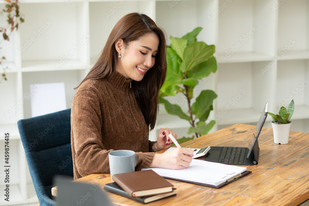 Beautiful smiling Asian female blogger dressed casual sitting and using laptop computer on the wood 