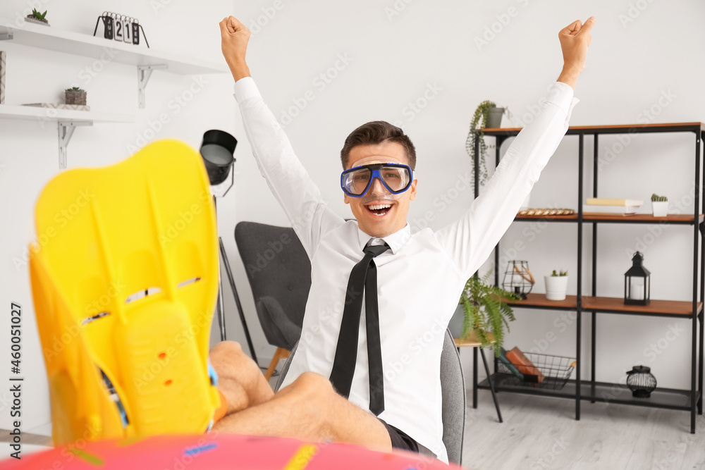 Happy man with snorkeling mask and paddles dreaming about vacation in office