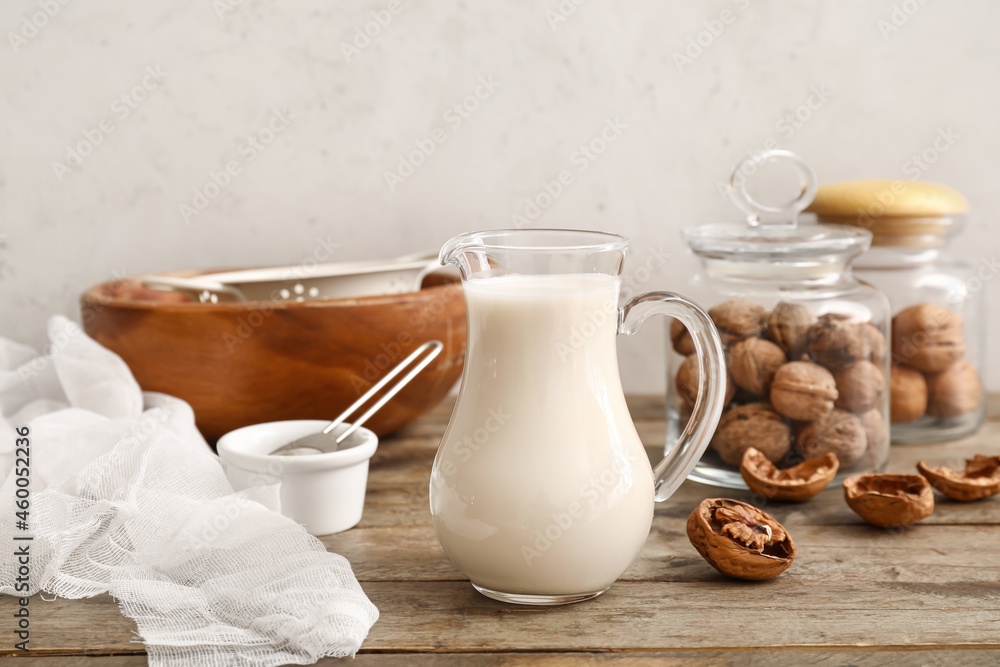 Jug with tasty walnut milk on kitchen table