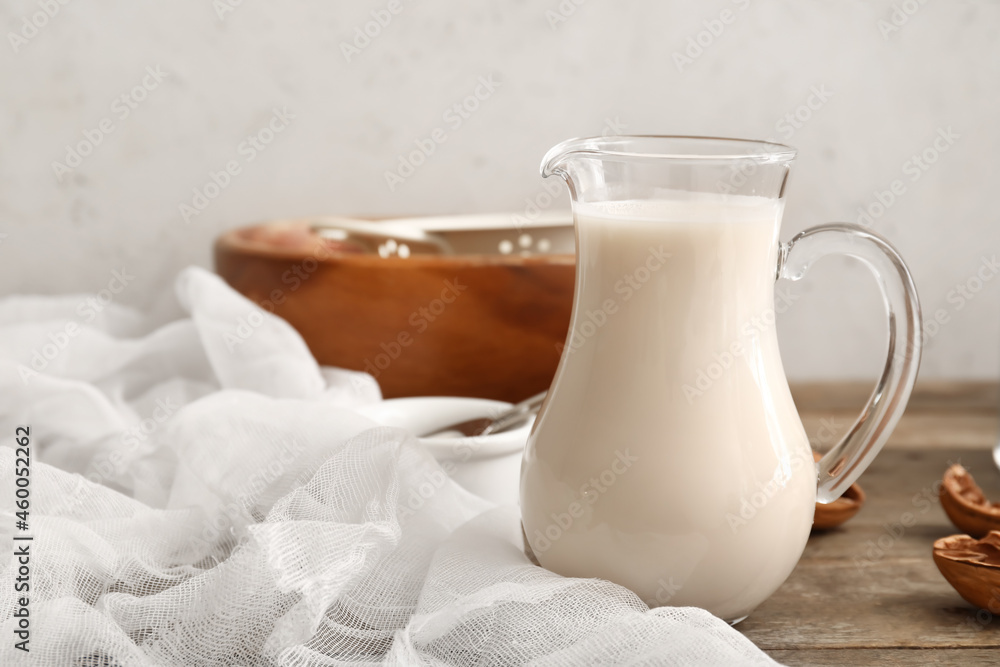 Jug with tasty walnut milk on kitchen table