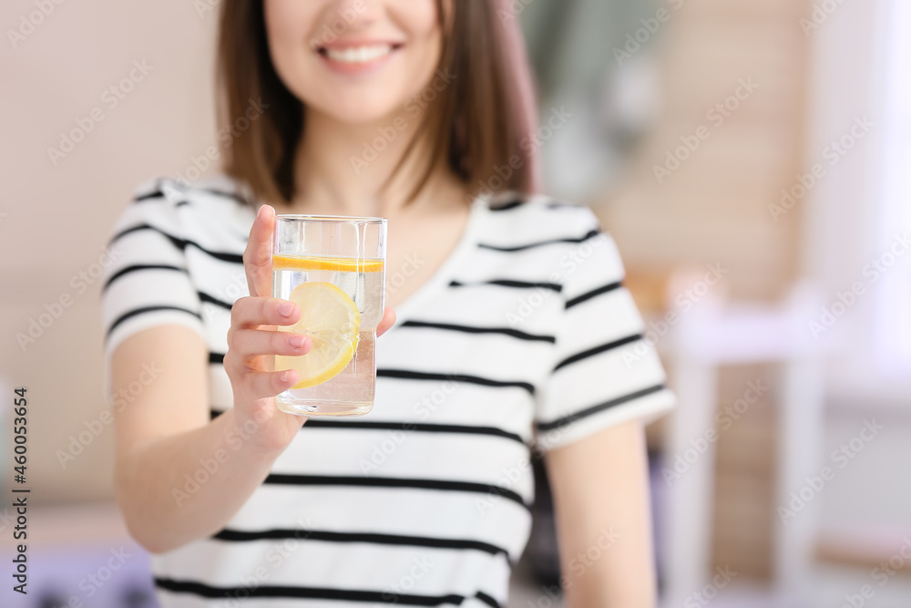 Beautiful young woman with fresh lemonade at home