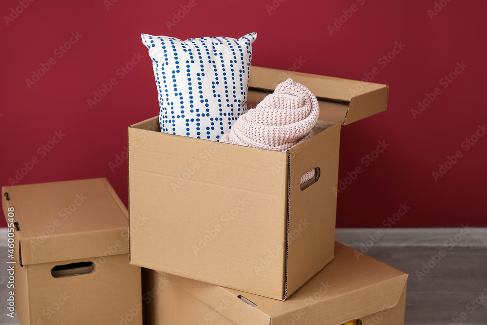 Wardrobe boxes with pillow and plaid on wooden floor near color wall