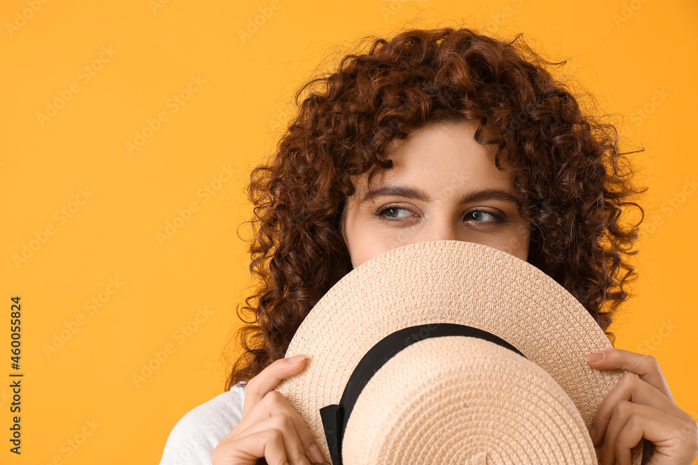 Beautiful woman holding boater hat on yellow background