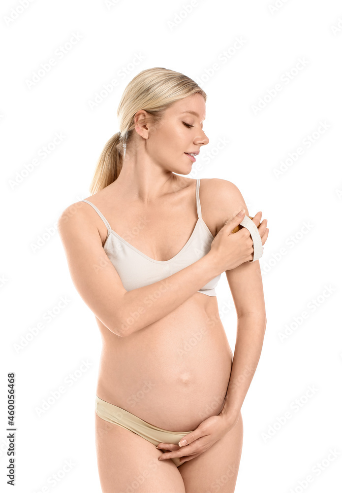 Beautiful pregnant young woman with massage brush on white background