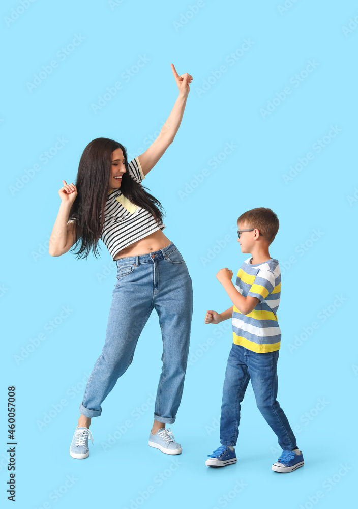 Dancing young woman and her little son on color background