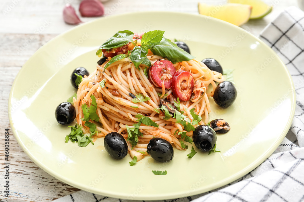 Plate of tasty Pasta Alla Puttanesca on white wooden background