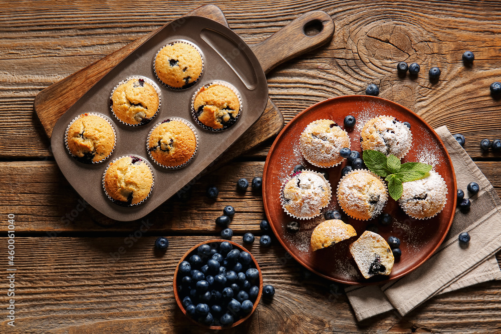 Composition with tasty blueberry muffins and berries on wooden background