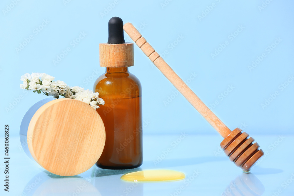 Cosmetic products, honey and dipper on color background