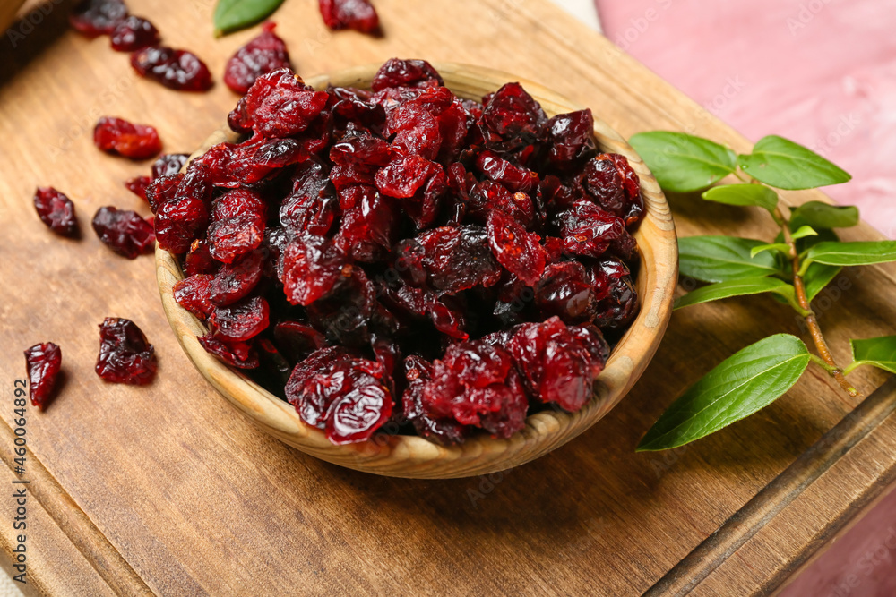 Bowl with tasty dried cranberries on table, closeup