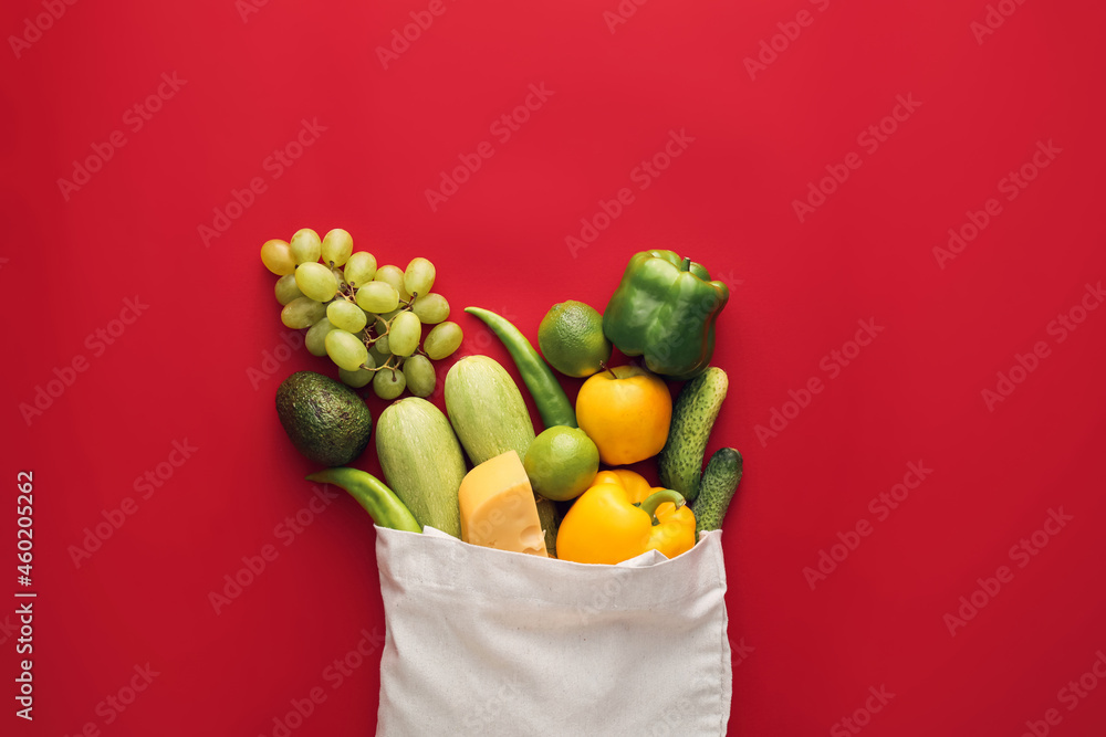 Eco bag with fruits, vegetables and cheese on color background