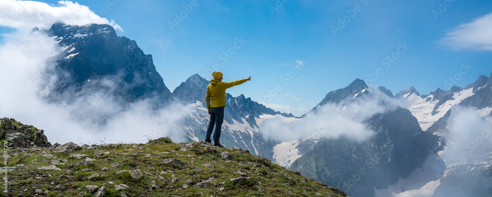 背着背包站在山顶享受阳光的徒步旅行者