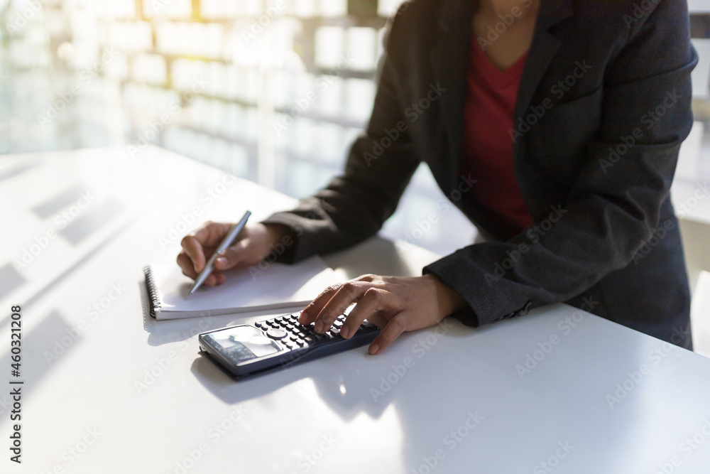 Businesswoman calculates expenses and writes a memo.