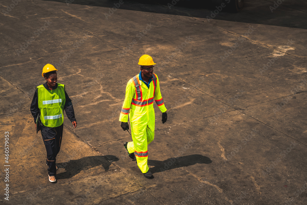 Industrial worker works with co-worker at overseas shipping container yard . Logistics supply chain 