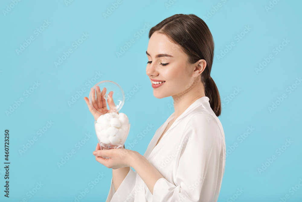 Beautiful young woman with cotton wool on color background