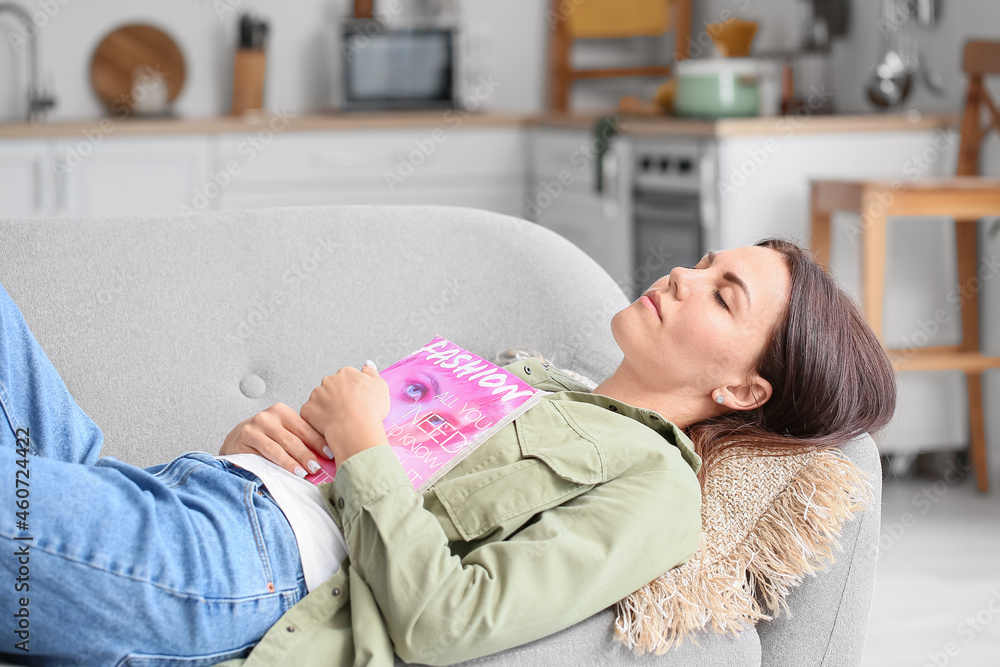 Young woman with magazine sleeping on sofa