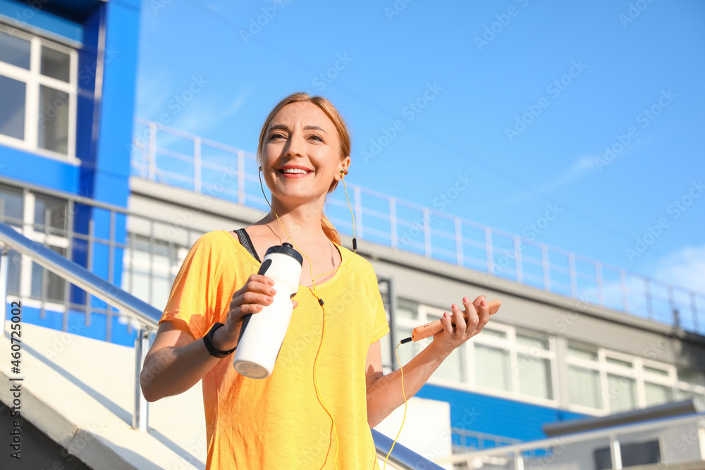 带着一瓶水在户外听音乐的运动型成熟女性