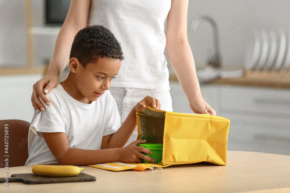 Mother and her little son putting lunch in bag before school