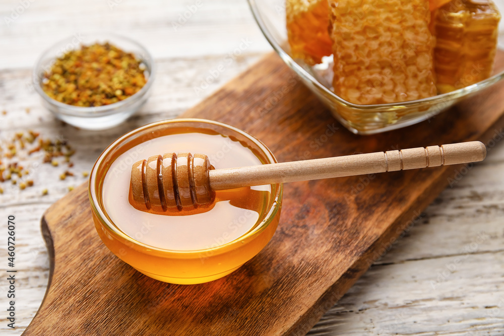 Bowl of honey on white wooden background