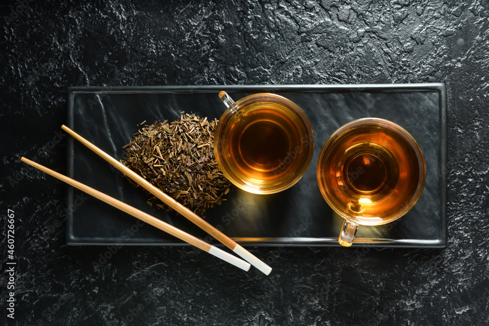 Glass cups of tasty hojicha green tea on black background