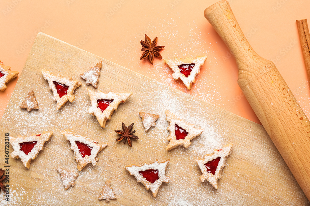 Board with tasty Linzer cookies and rolling pin on color background