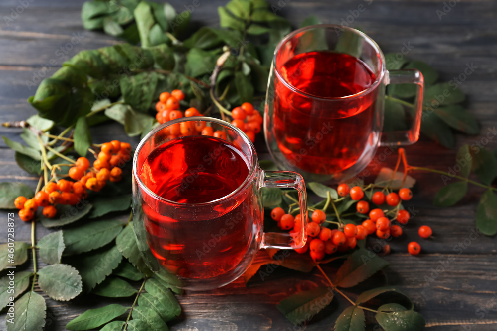 Cups of delicious rowan tea and berries on wooden background