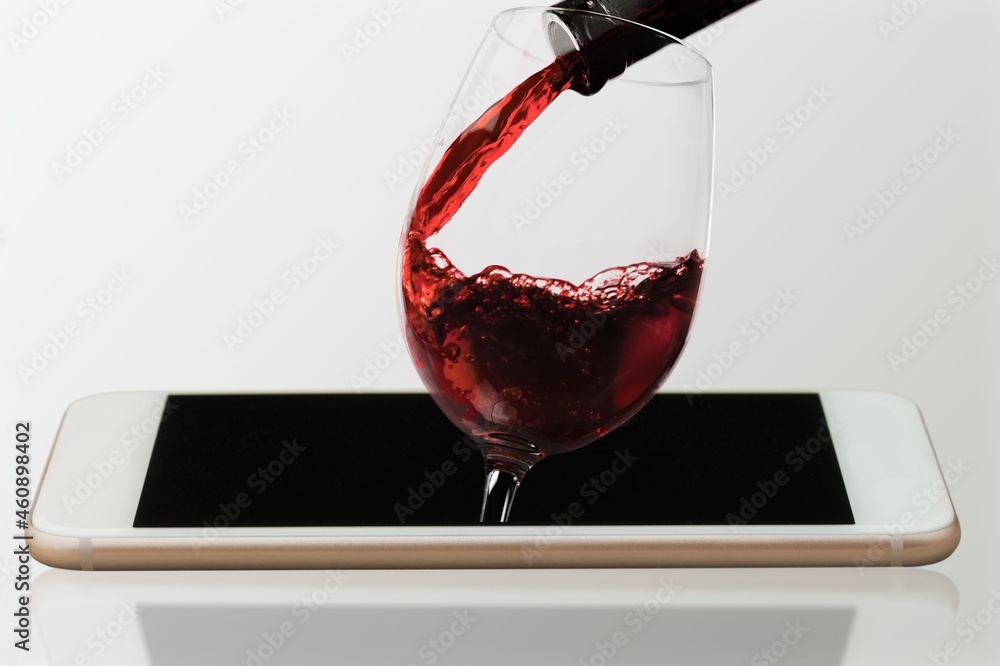 Modern artwork. Glass filling with wine from a bottle in phone screen