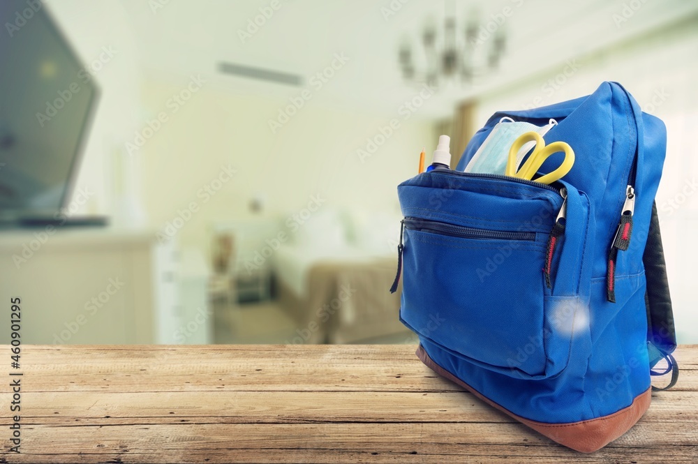 Classic school backpack with different school stationery on background