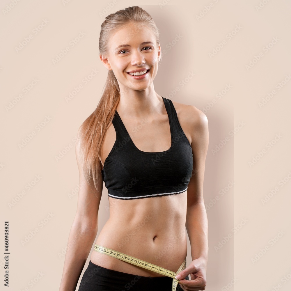 Beautiful young woman with measuring tape after weight loss on the background