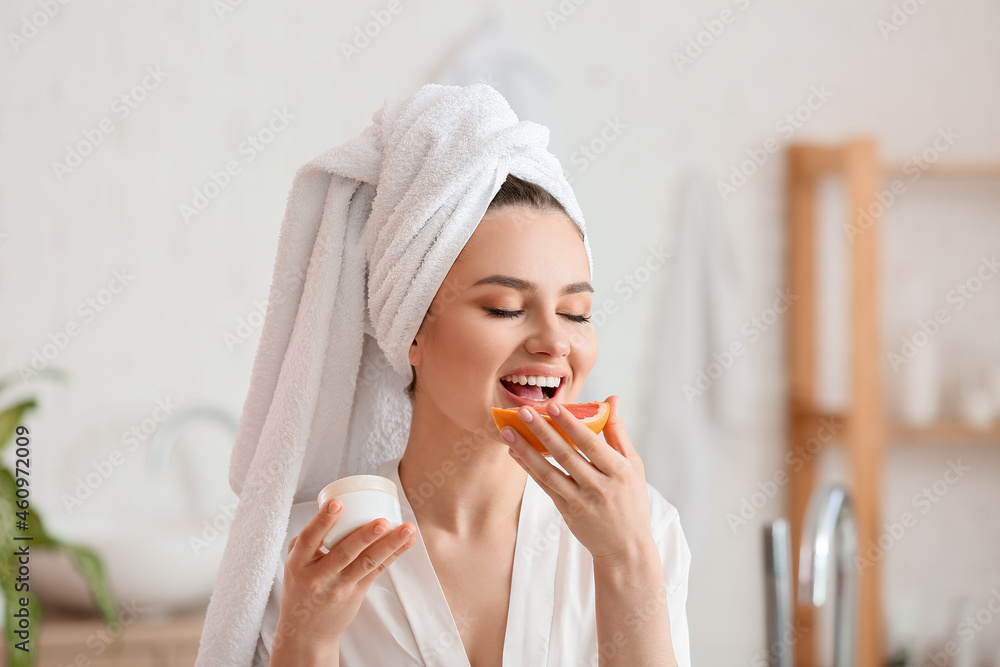 Beautiful young woman with grapefruit and cream in bathroom