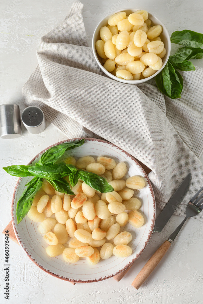 Plate and bowl with tasty gnocchi on light background