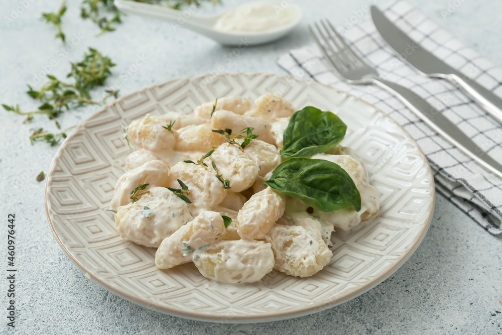 Plate of tasty gnocchi with creamy sauce on white background