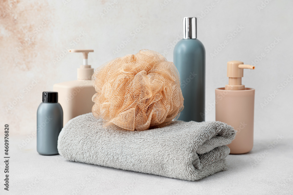 Composition with cosmetic products, towel and soft bath sponge on light background