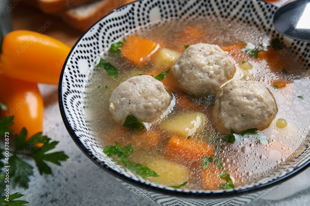 Bowl with tasty meatball soup on table, closeup