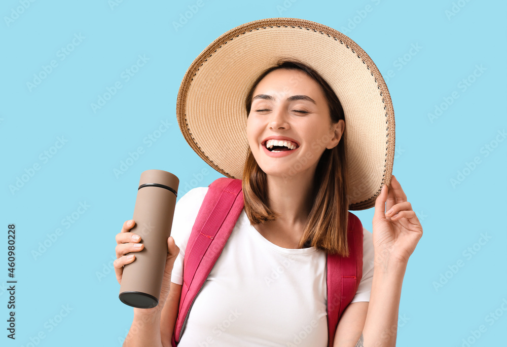 Female tourist with thermos on color background