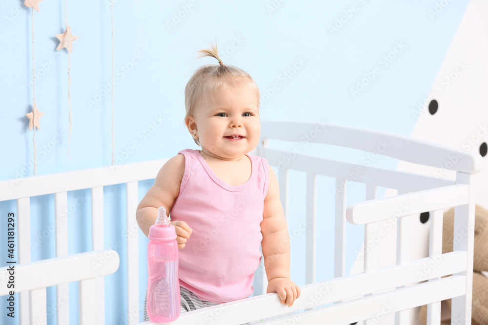 Cute baby girl with bottle of water in cot