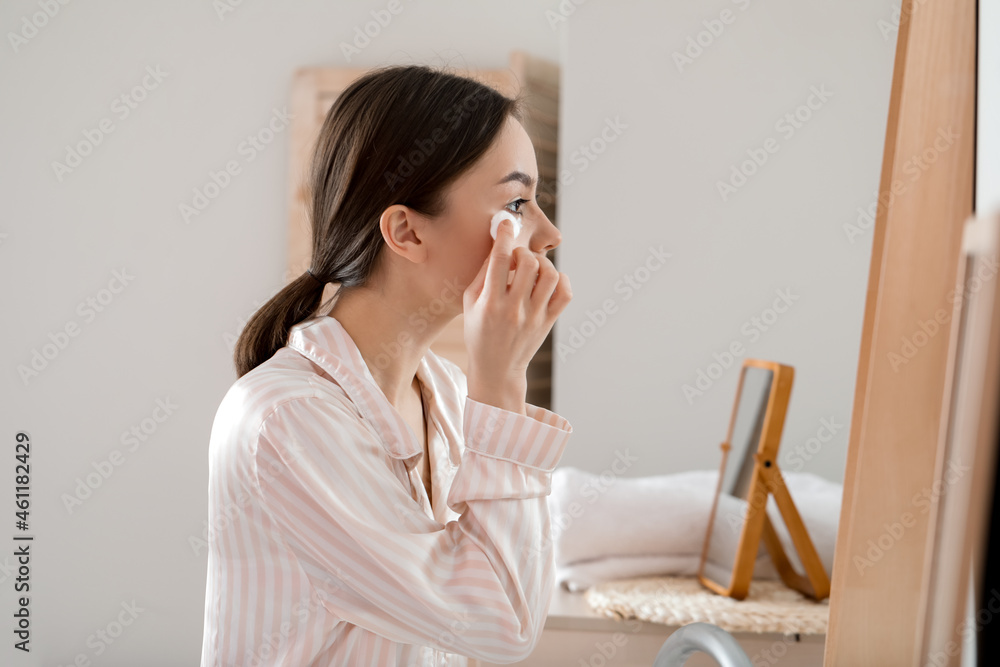 Beautiful young woman with cotton wool in bathroom