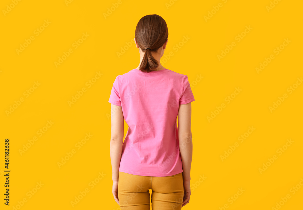 Young woman in modern t-shirt on color background, back view